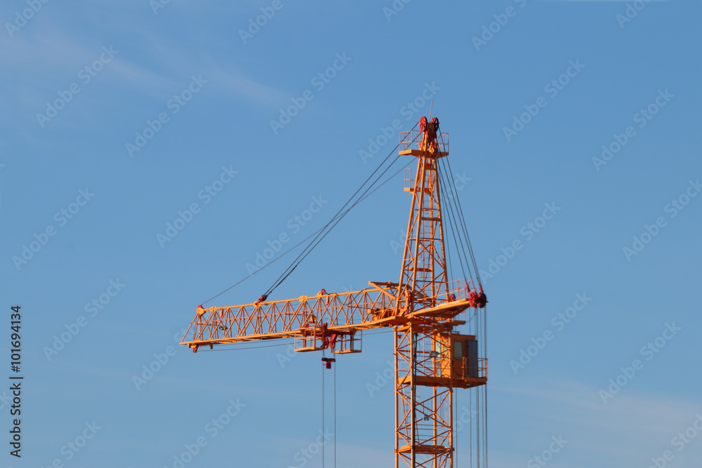 Tall yellow stationary hoist construction site and blue sky 