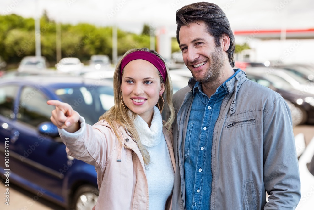 Composite image of smiling couple looking and pointing