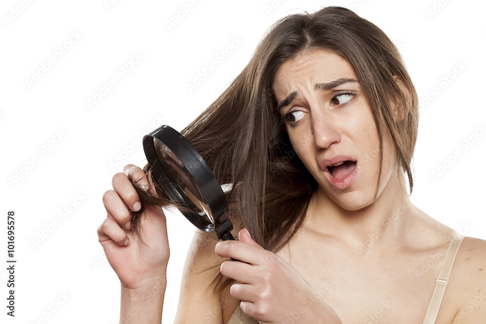 unhappy young woman looking at her hair through the lens unhappy young woman looking at her hair through the lens