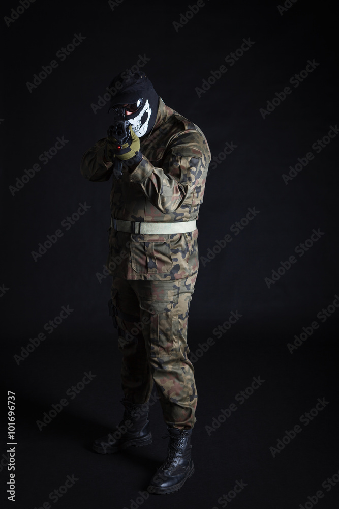 Anti terrorist dressed in camouflage, aiming with a gun at camera