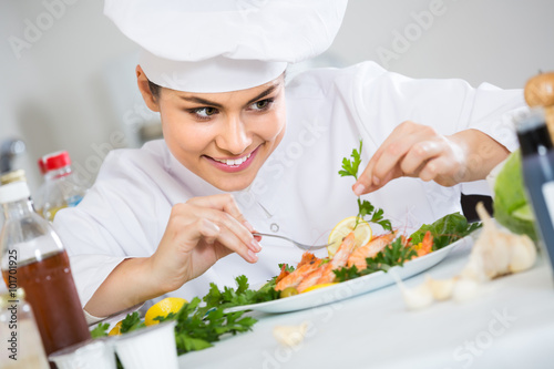 Professional cook decorating prepared dish of shrimps
