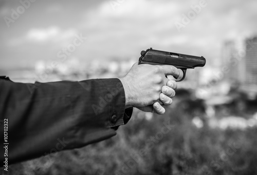 Man hand holding gun. Selective focus with shallow depth of field. Black and white toning.