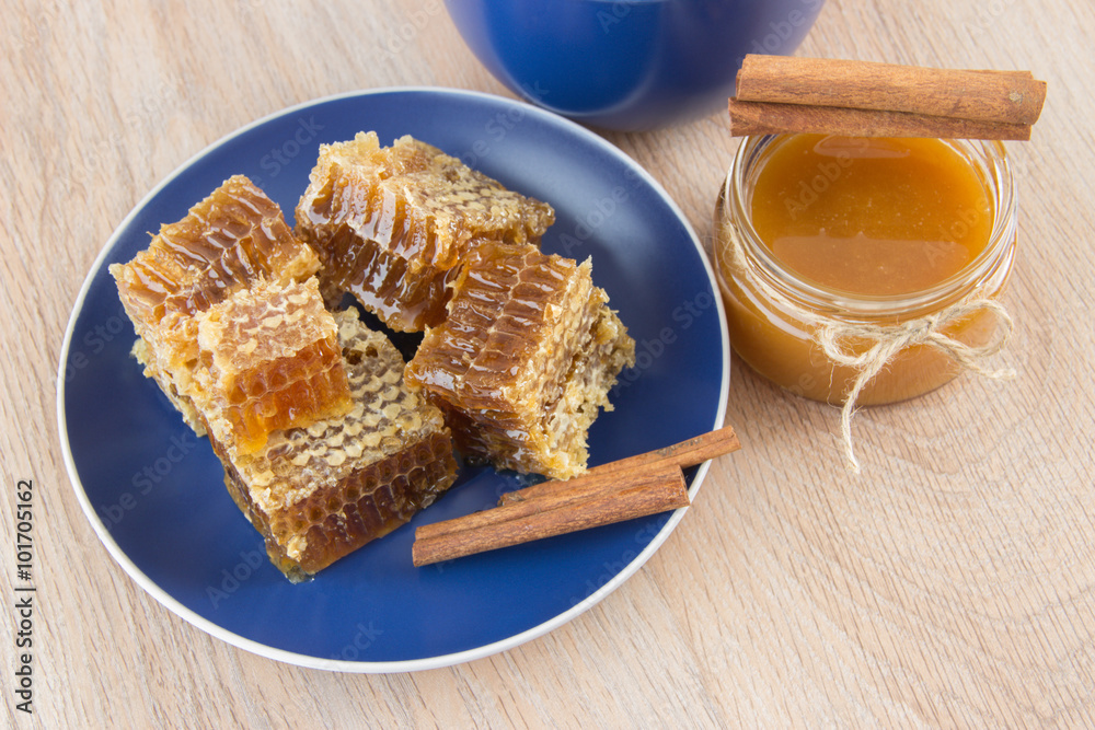 Pieces of golden honey comb on a table with tea, lemon and cinna Pieces of golden honey comb on a table with tea, lemon and cinna