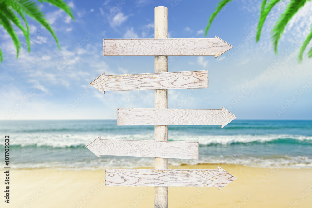 Fotografie White wooden arrows-pointers at ocean with beach background