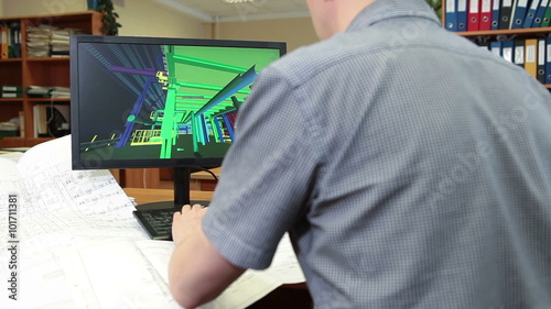 Rear view of an architect working at desk with 3d model visualisation