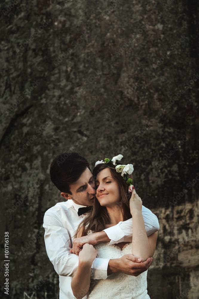 happy elegant groom hugging and kissing stylish boho bride at su happy elegant groom hugging and kissing stylish boho bride at su