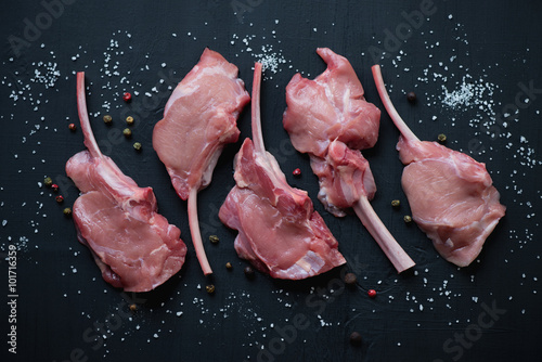 Top view of raw bobby veal rack steaks on a black wooden surface photo