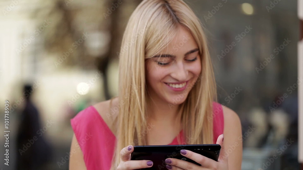 Cute smiling lady using fashionable digital tablet on the street Cute smiling lady using fashionable digital tablet on the street