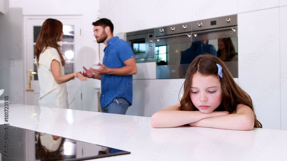 Sad girl looking down while parents are arguing Sad girl looking down while parents are arguing