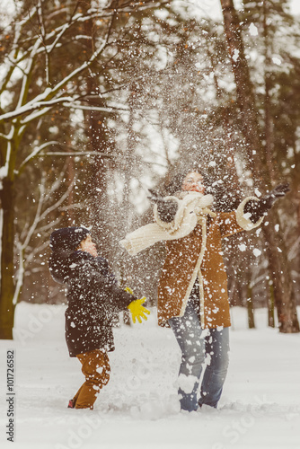 Happy family in warm clothing. Smiling mother and son playing fun game outdoor. The concept of winter activities