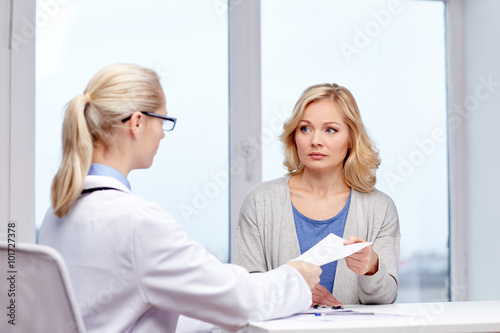 doctor giving prescription to woman at hospital