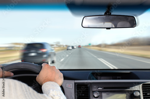 Hand of man driving on a highway.