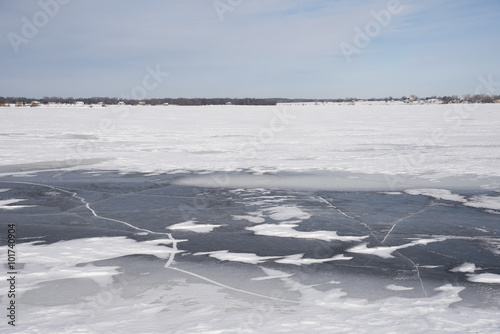 Dark, cracked ice has been exposed after the wind blew snow clear of frozen lake.