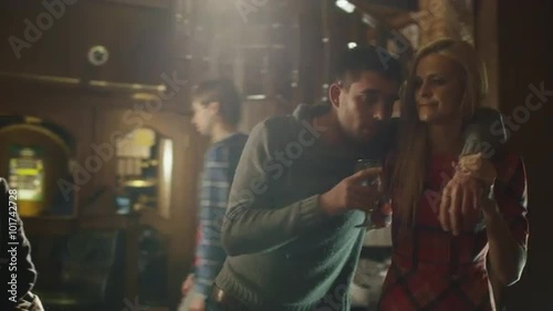 Young woman is helping her drunk friend with beer glass to go away from the bar. Shot on RED Cinema Camera.