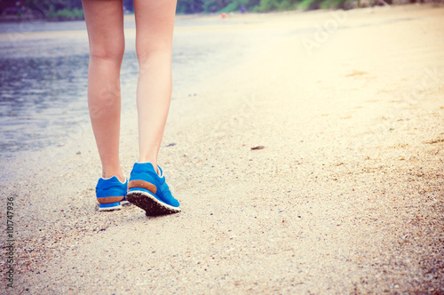 Women's legs running or walking along the beach.