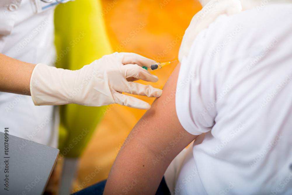 Teenage boy getting vaccination in his arm, close up Teenage boy getting vaccination in his arm, close up