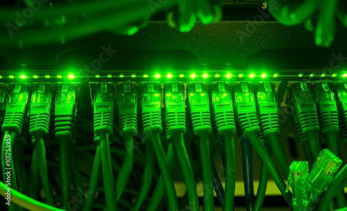 Close up of green network cables connected to switch glowing in the dark photo