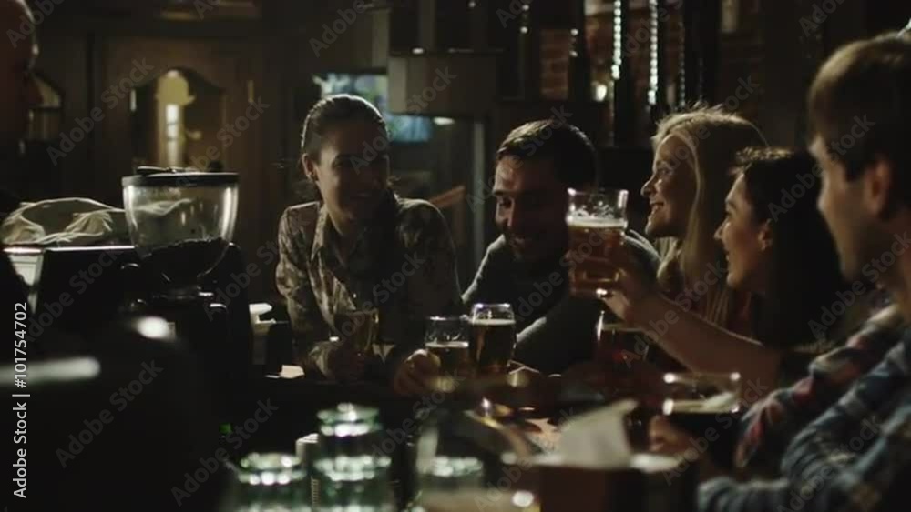 Friends do toasts, drink beer and cocktails while having a good time together at a dark bar. Shot on RED Cinema Camera. Friends do toasts, drink beer and cocktails while having a good time together at a dark bar. Shot on RED Cinema Camera.