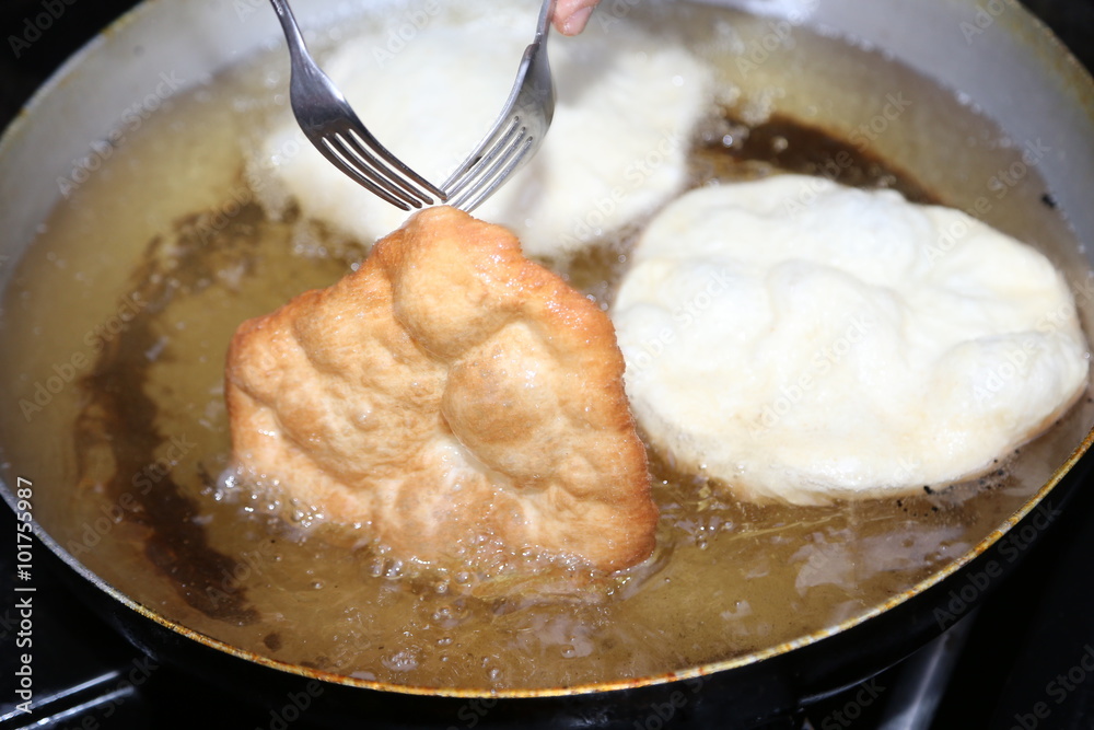Φωτογραφία cooking the big fried fritters dipped in hot oil in an aluminum