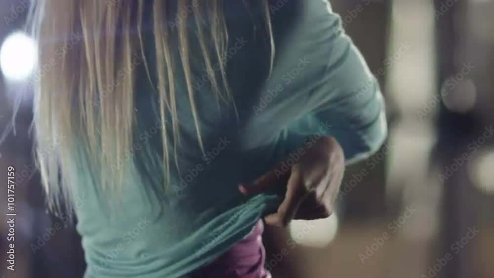 Attractive fit sporty girl is taking off her sweatshirt in the gym. Shot on RED Cinema Camera.