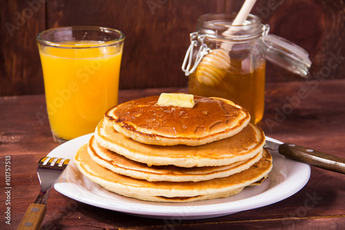 Pancakes and orange juice on a white plate 