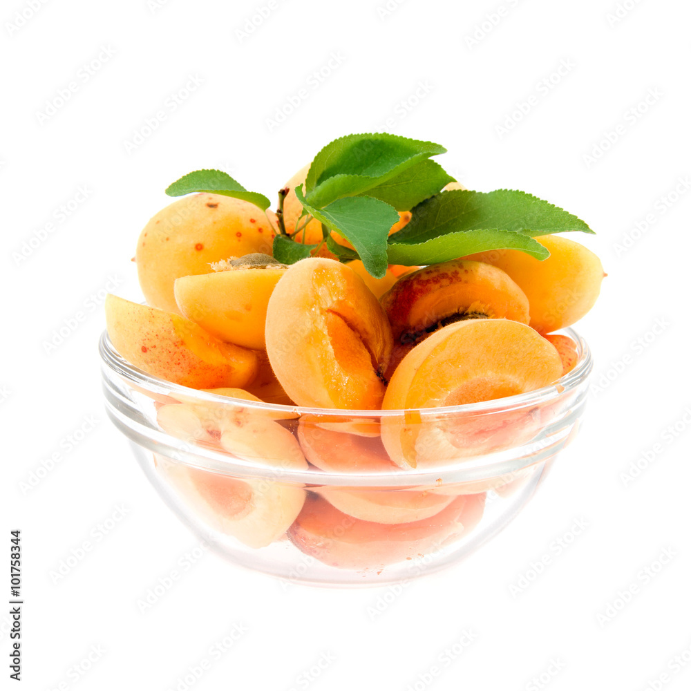 apricot halves with leaves in a transparent plate on a white bac apricot halves with leaves in a transparent plate on a white bac