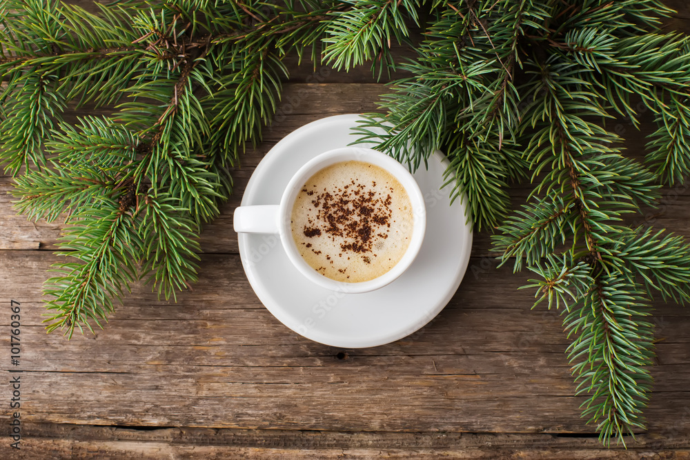 A cup of coffee with the branches of the Christmas tree on a woo A cup of coffee with the branches of the Christmas tree on a woo