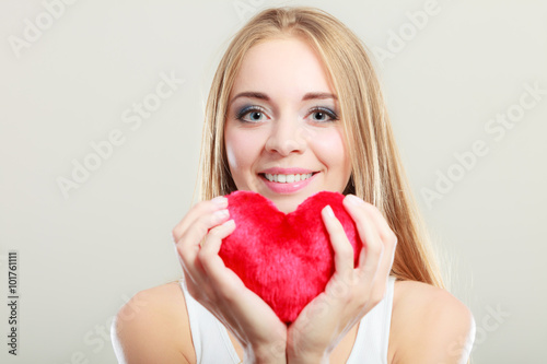 Smiling woman holding red heart love symbol