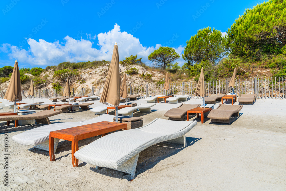 Sunbeds on Palombaggia beach on sunny summer day, Corsica island, France