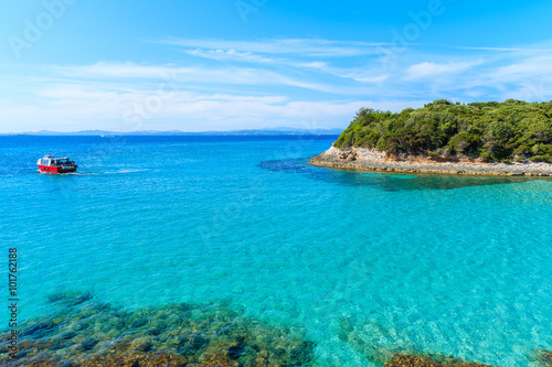 Tourist boat cruising on turquoise sea water near Petit Sperone bay, Corsica island, France