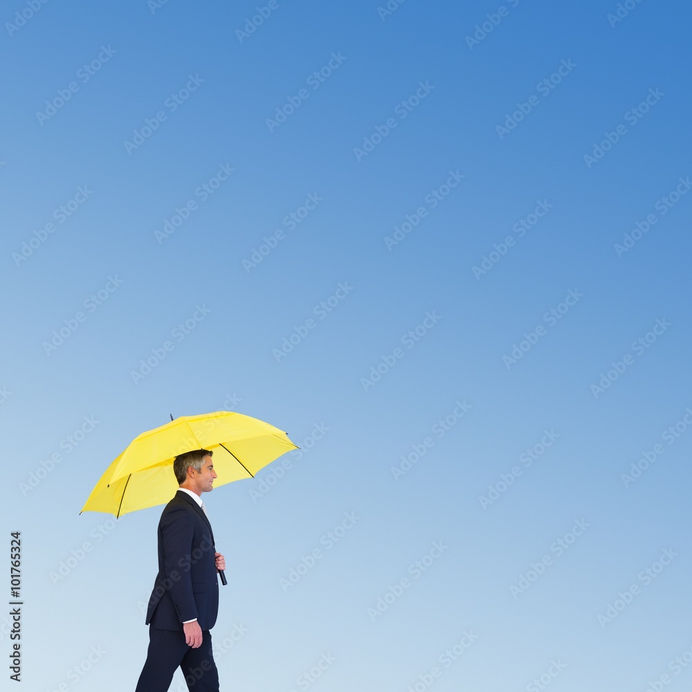 Composite image of businessman with yellow umbrella walking 