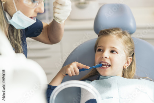 Doctor dentist teaching a child to brush teeth.