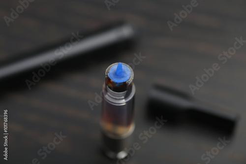 Cannabis oil dispenser/electronic cannabis oil vaporizer with oil-filled cartridge on wood surface