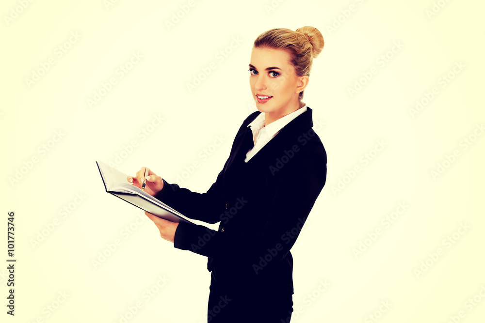 Young businessoman holding notebook and writes something