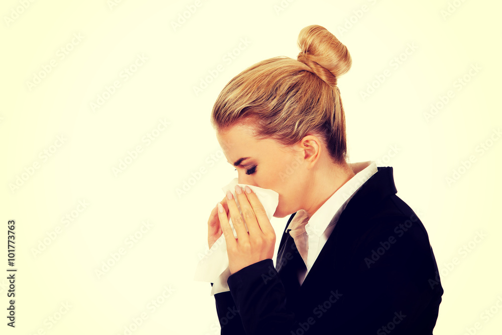 Businesswoman with an allergy sneezing into tissue Businesswoman with an allergy sneezing into tissue