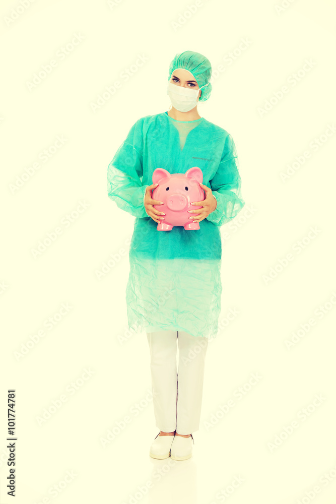 Female surgeon doctor holding piggy bank Female surgeon doctor holding piggy bank