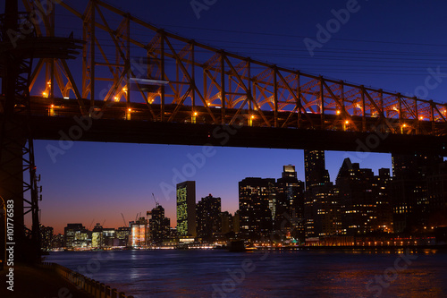 Manhattan and Roosevelt Island bridge at night in New York, USA. A view on Manhattan from the East River bank at night.