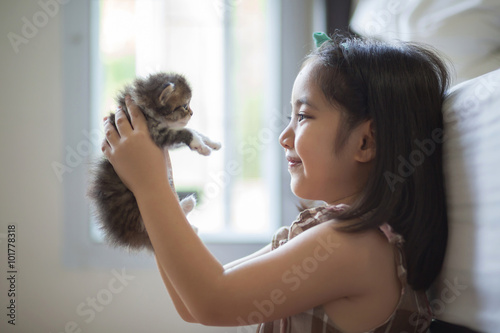 Adorable little asian girl kissing her kitten