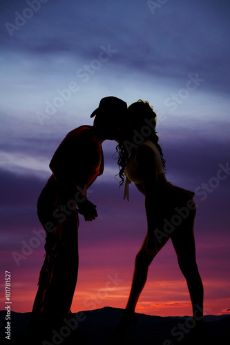 Silhouette of woman in short skirt kiss cowboy