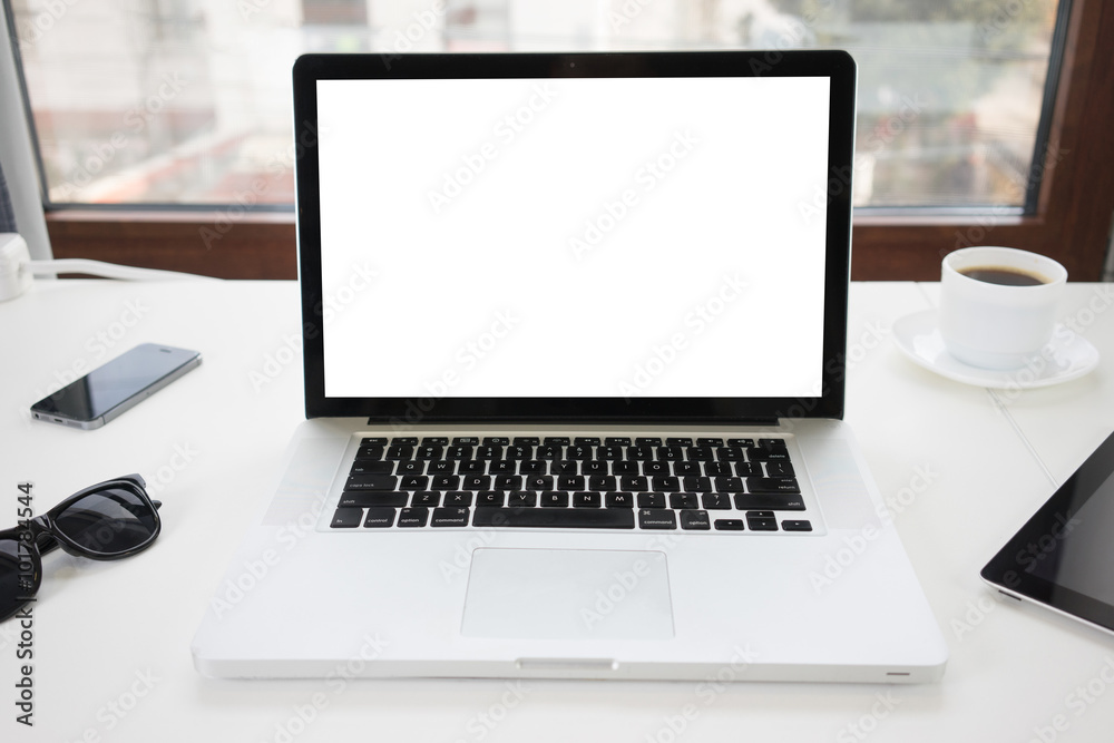 Office desk next to a window with laptop and tablet pc and a sma Office desk next to a window with laptop and tablet pc and a sma