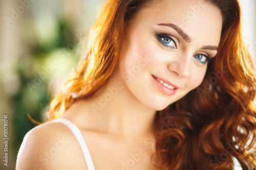 Closeup portrait of redhead young woman with curls and perfect makeup