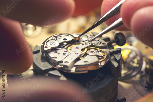 Working On A Mechanical Watch. A watch makers work top. The inside workings of a vintage mechanical watch. photo