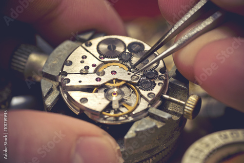 Working On A Mechanical Watch. A watch makers work top. The inside workings of a vintage mechanical watch. photo