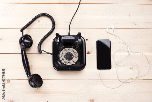 Old retro black phone and new cell phone on wooden board, top view, DOF, focus on phone