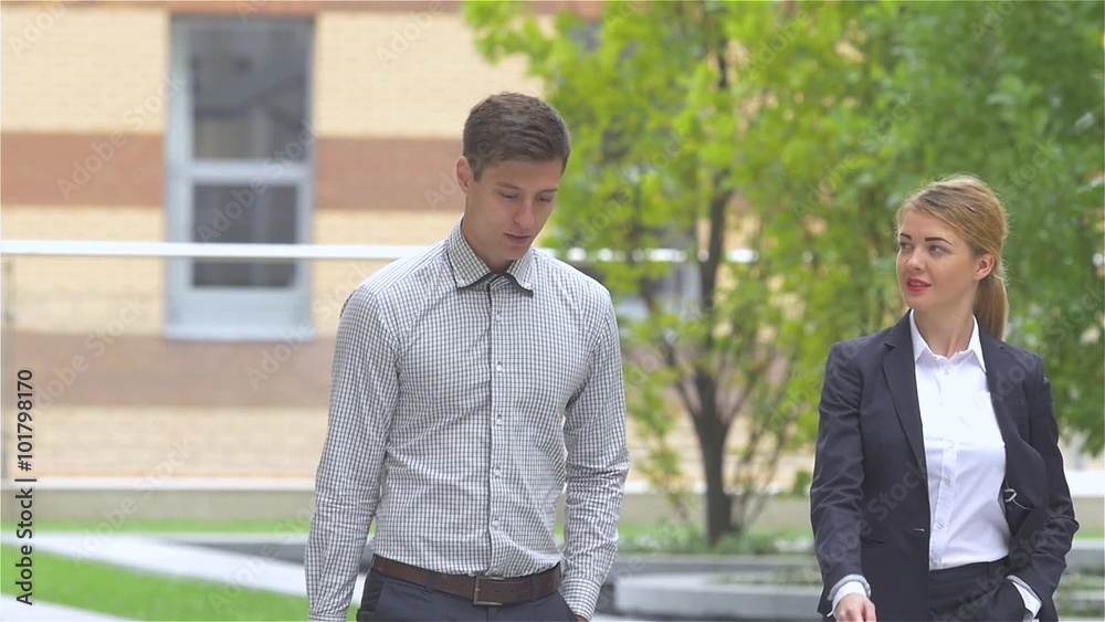 young businessman and businesswoman walking on the street of an business center, slow motion young businessman and businesswoman walking on the street of an business center, slow motion