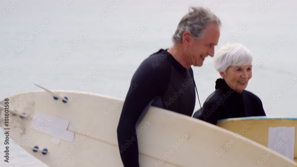 Retired couple walking with surfboards Retired couple walking with surfboards