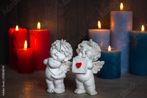 2 angel statuettes with a love letter and burning candles