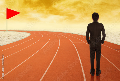 businessman standing on running track and looking to goal