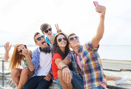 happy friends with smartphone taking selfie