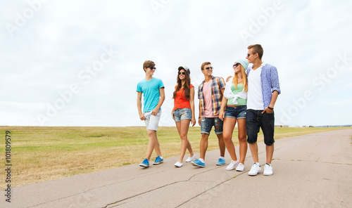 group of smiling friends walking on road